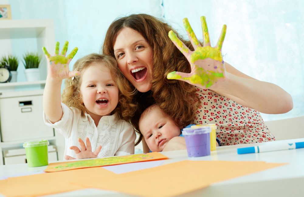 Portrait of a happy family having fun painting with palms and fingers